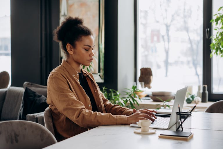 Woman in a Brown Long Sleeve Shirt Typing on Her Laptop