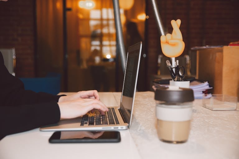 Close-up of virtual assistant hands typing on a laptop in a modern home office setting
