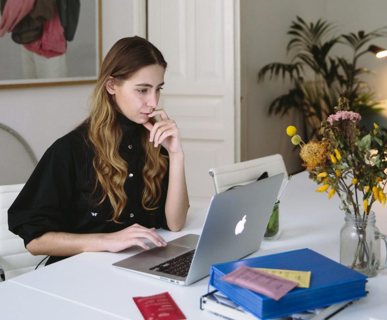 Woman working on a laptop at home, embracing a digital nomad lifestyle as a virtual assistant.
