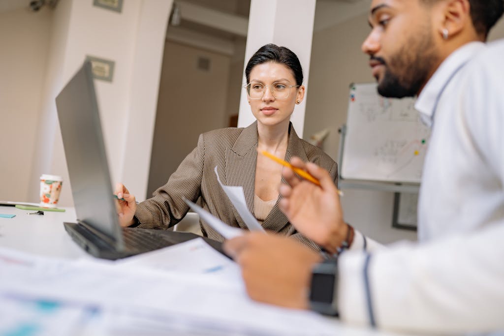 Business executive collaborating in a modern office, engaged in new executive assistant training in front of computer and documents.